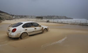 epa04714091 A car sits covered in sand in the car park next to the Bondi Beach promenade, which is covered in sand blown inland during heavy storms in Sydney, Australia, 21 April 2015. More than 20 people have been rescued from floodwaters and 215,000 homes and businesses are without power as storms continue to lash South Eastern Australia.