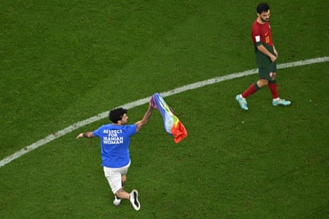 A man invades the pitch holding a LGBT flag as he wears a t-shirt reading 