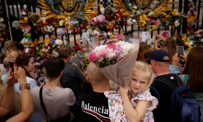 People take photographs and leave flowers at the gates of Buckingham Palace.
