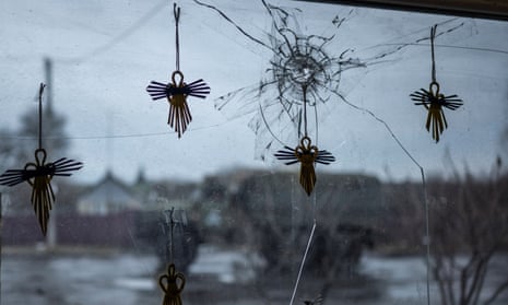 Angel figurines on a window of a local grocery store broken by shrapnel while a Ukrainian army truck moves past