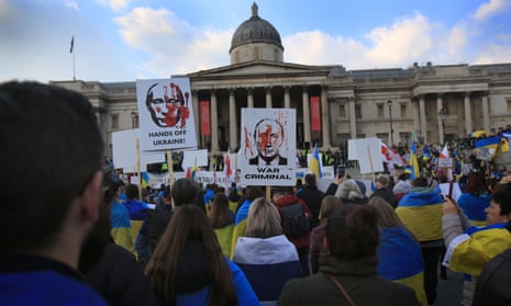 Protesters hold signs accusing Vladimir Putin of war crimes at a demonstration in London