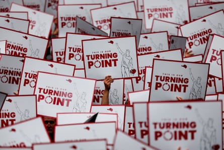 a sea of red and white signs saying ‘this is our turning point’ with an illustration of charlie kirk
