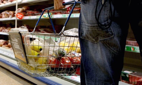 A person holds a shopping basket in a supermarket.