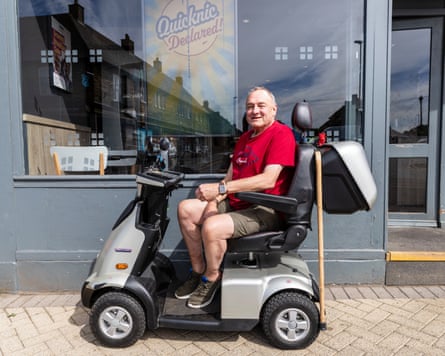 Martin Harvey sitting on a mobility scooter outside a shop.