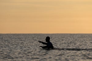 A person more than waist deep in the sea in early morning light