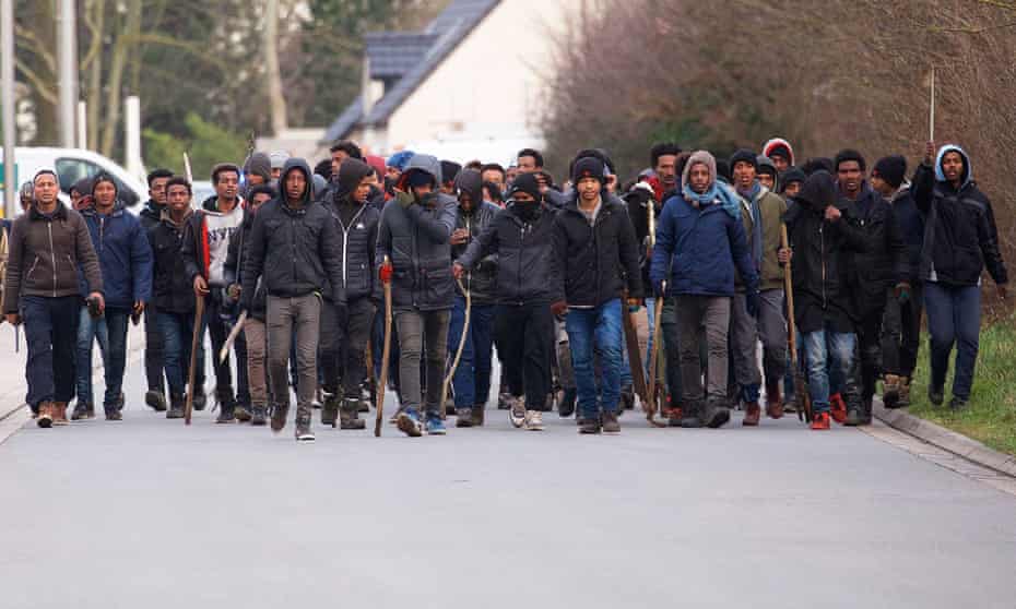 Migrants carry sticks during clashes near the ferry port in Calais on Thursday after at least five migrants were shot while queuing for food.