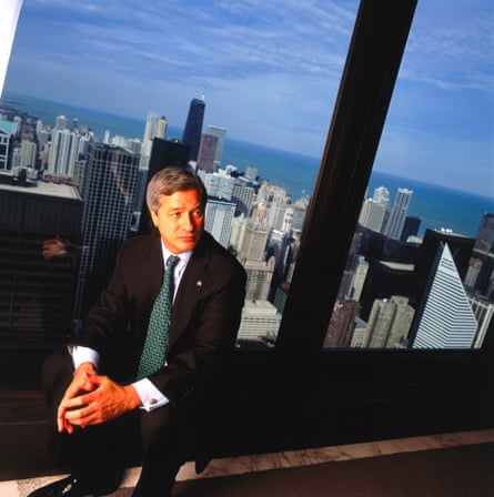 a man in a suit sits in a building with a city skyline visible behind him