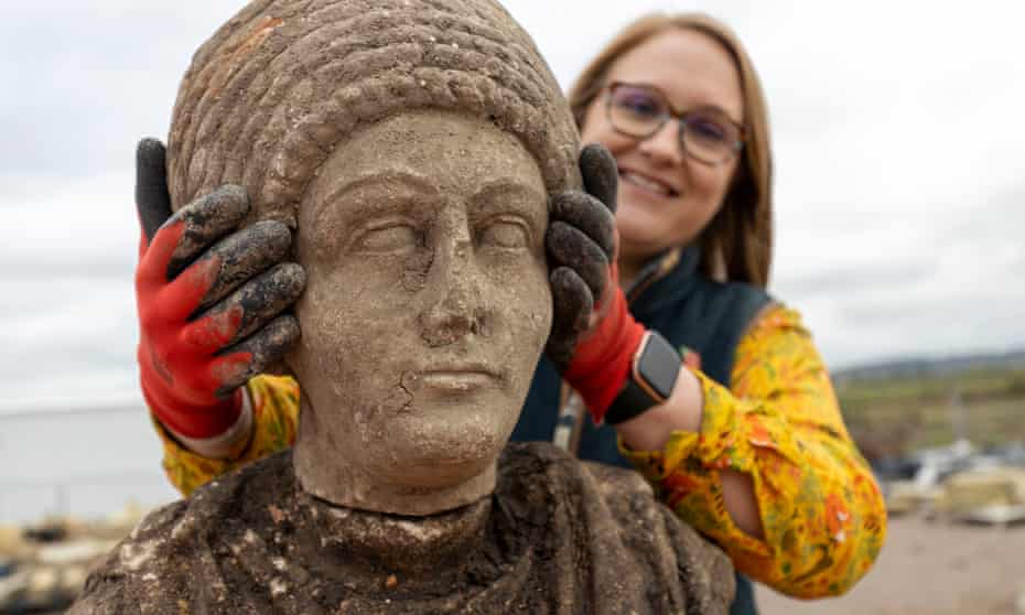 An archaeologist holds the statue of the head and shoulders of a Roman woman.