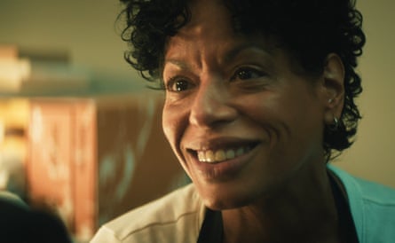 A woman of colour who is wearing a white top and smiling