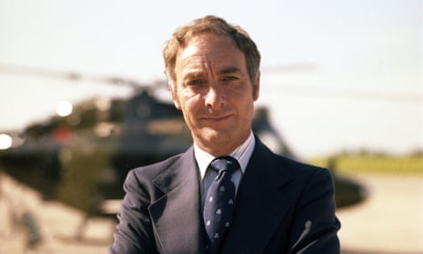 Don Berrington stands in front of a helicopter, wearing a suit and tie