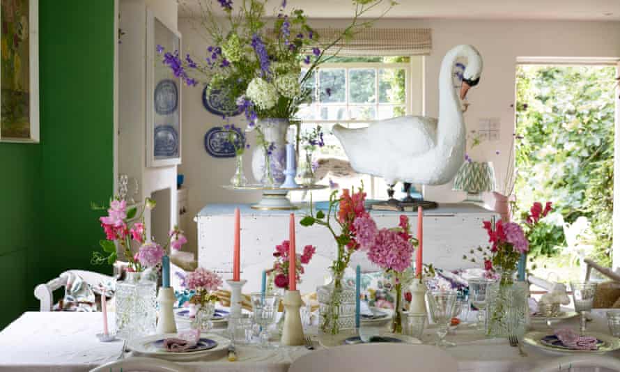 A set table with flowers and candles, a large model of a swan behind and dark green paint on the walls