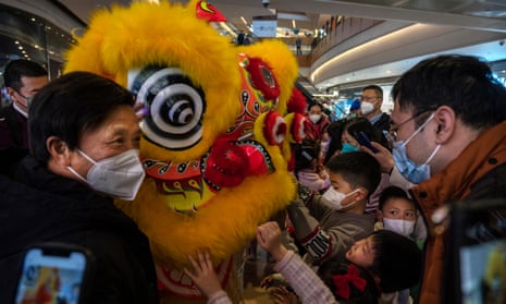 Masked crowds gather around a lion dancer during lunar new year activities in Beijing