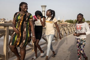 Girls walk along a bridge from the island of Fadiouth