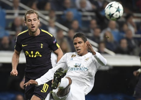 Real Madrid’s French defender Raphael Varane (R) clears the ball as Spur’s striker Harry Kane hovers nearby.
