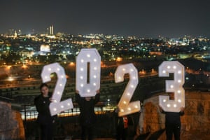 People hold a 2023 installation as they celebrate New Year’s Eve at Mount of Olives overlooking Jerusalem’s Old City