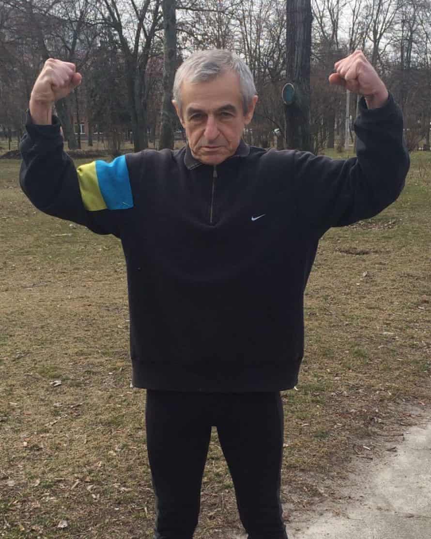 An old man wearing black clothes flexing his arms