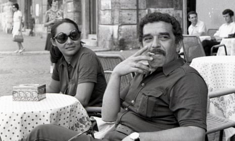 García Márquez sits at pavement cafe table, smoking cigarette, in short-sleeved shirt. Woman in dark glasses sits next to him