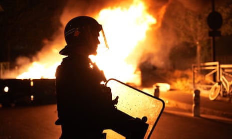 A police officer looks on as vehicles burn following riots in Nanterre, west of Paris, on June 28, 2023