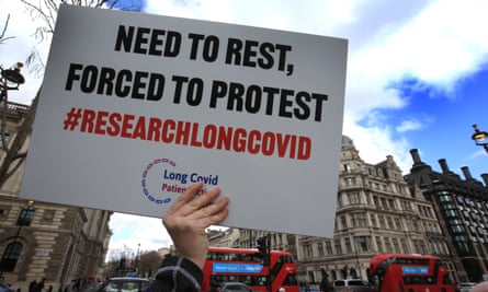 A protester holds up a placard reading: ‘Need to rest, forced to protest. #ResearchLongCovid’