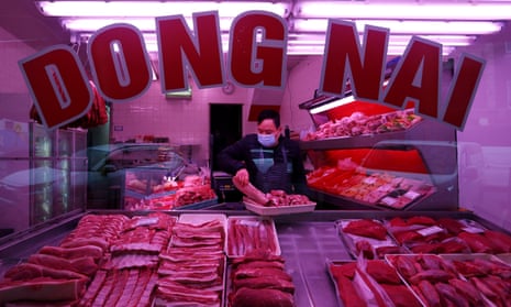 A butcher wears a mask whilst setting up a meat display