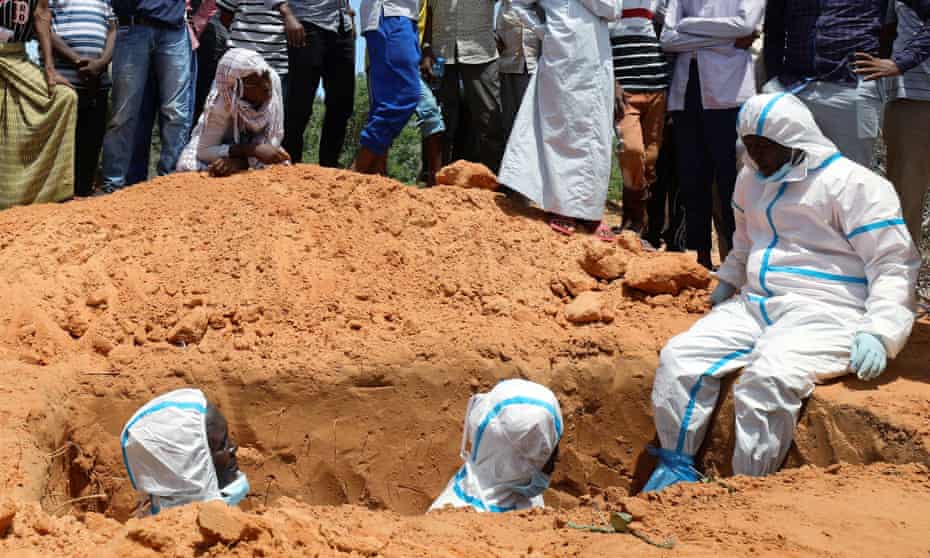 Somali workers in protective suits stand inside a grave in Mogadishu.