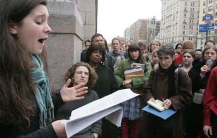 A young woman speaks to a crowd while looking at sheets of paper on the streets of New York City