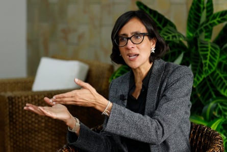 A seated middle-aged Latina woman gestures as she speaks
