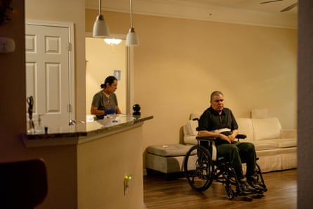 Woman stands in home’s living room behind man sitting in wheelchair