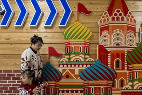A woman and a young girl walk past a colourful wall decoration made up of onion-domed, Russian-style cathedrals