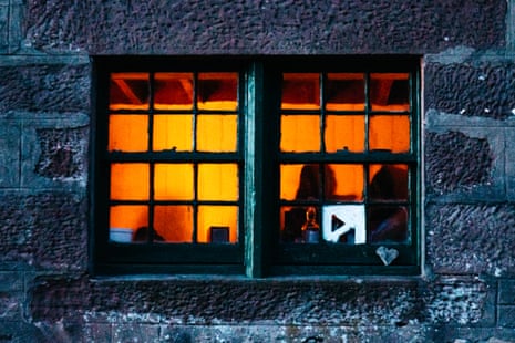 Seen from outside, a bothy window glows with the light of a fire.