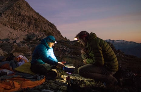 Mountaineers cooking on camp stove and using headlamps after sunset
