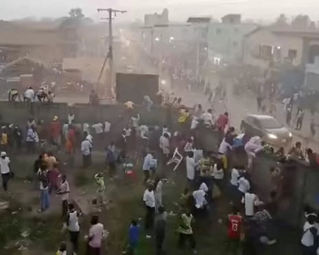 People clamber over a wall into streets outside the stadium
