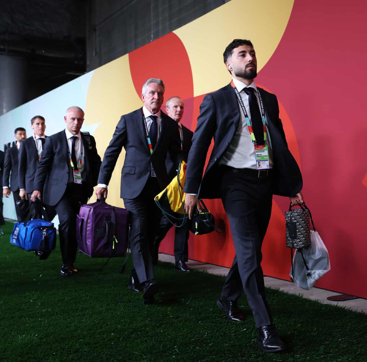 The Socceroos walking in suits and holding bags