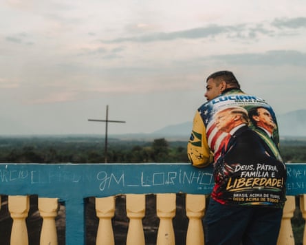 A man wearing a shirt with images of Donald Trump and Flávio Bolsonaro on the back