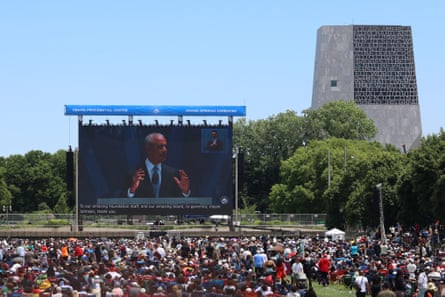 Crowds watch a screen, with the tower of the library beyond them.