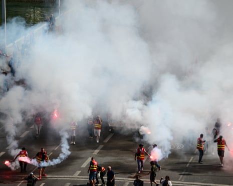 Wide view of a street with protesters carrying flares