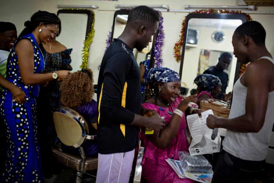 Young men who have come to Conakry’s Miskaa Salon for cut price condoms are shown how to use them correctly by apprentice hairdresser Nene Diakité.