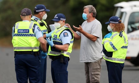 A traveller talks with police as they check travellers’ vaccination passes and Covid tests in Auckland.