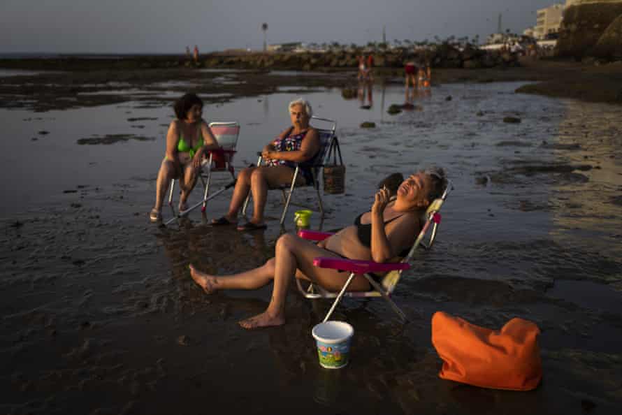 People sunbathe at sunset in a beach in Chipiona, a town and municipality located on the Atlantic coast in the province of Cadiz, Spain.