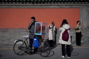 A vendor sells sugar-coated Chinese haws on his bicycle as visitors pose for photographs with their haws outside the Drum Tower in Beijing
