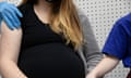 Pregnant women in black top has vaccine, while holding hand of companion