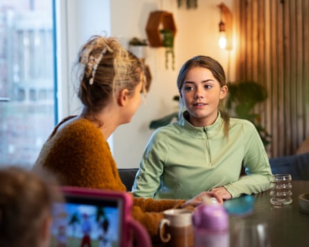 mother and teenage daughter sat at a table talking