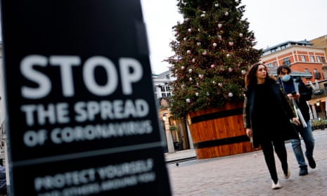 Pedestrians pass a coronavirus warning sign in Covent Garden in central London