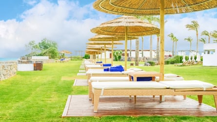Row of sunloungers connected writer underneath writer umbrellas