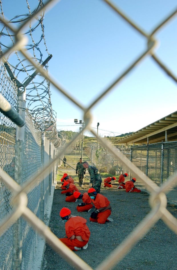Detainees sit in a holding area under the surveillance of US military police at Guantánamo in January 2002.