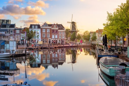 historic Dutch town centre with windmill and canal reflecting in Rhine river on sunrise