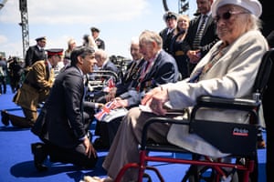 Rishi Sunak kneels in front of some D-Day Normandy veterans