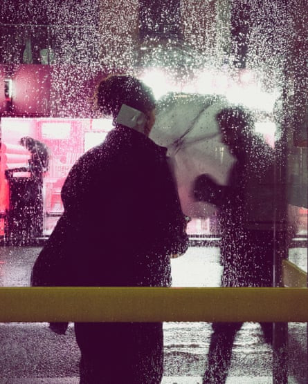 Una mujer se para en una parada de autobús lluviosa por la noche