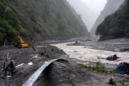 Excavators clear debris to restore a road next to a river in a mountainous area