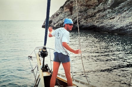 Frolec stands on the boat, wearing shorts and T-shirt with a bandanna on his head.